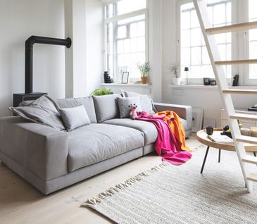 Helle Farben lassen kleine Räume leichter und Größer wirken Hellgraues 2-Sitzer-Sofa in hellem Wohnzimmer mit beigem Teppich