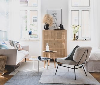 Weißes Sofa, helle Kommode und grauer Sessel mit Sommerflair