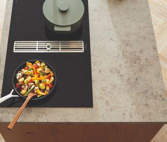 Gemüse in einer Pfanne auf einem Kochfeld mit integriertem Dunstabzug