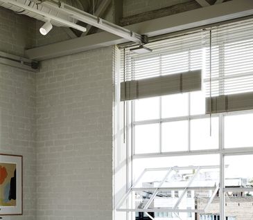 Blick hoch auf eine Decke, Fenster und Wänden einer alten Fabrikhalle mit Bildern an den Wänden