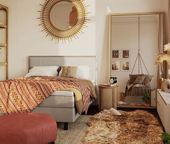 Schlafzimmer mit vielen Textilien im Boho Wohnstil: Schaffell, Boxspringbett aus Stoff, Kommode aus Holz und Hocker aus Velours