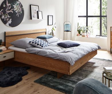 Bettgestell aus Massivholz Eiche vor dunkelgrünem Teppich