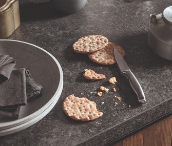Küchenarbeitsplatte aus dunklem Stein mit Crackern und Geschirr