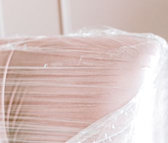 Schütze Schränke und Sofas mit Folie oder Pappe vor Schmutz und anderen Schäden Detailansicht einer Armlehne eines Sofas in Folie für den Umzug eingepackt