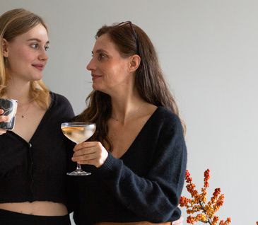 Tochter und Mutter trinken gemeinsam Glühwein vor herbstlicher Deko