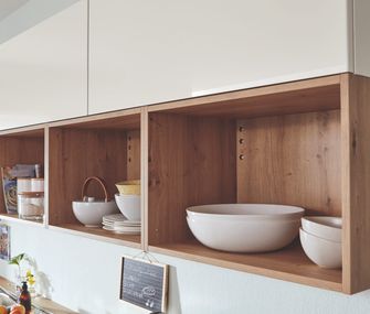 Weiße skandinavische Küche mit Holzregal und eingestautem Geschirr