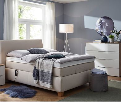 Beigefarbenes Boxspringbett im blau eingerichteten Schlafzimmer