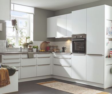 Weiße Küche in L-Form mit silberfarbenen Griffen und grauen Wänden