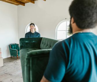 Ein Umzugsunternehmen entlastet dich besonders bei schweren und sperrigen Möbeln Zwei Männer eines Umzugsunternehmens tragen ein Sofa in die Wohnung