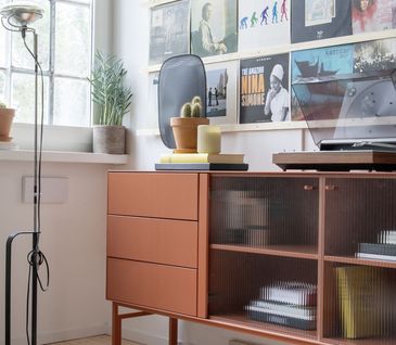 Sideboard im Retro-Look mit vor Wand mit Bildern von Vintage-Schallplatten.