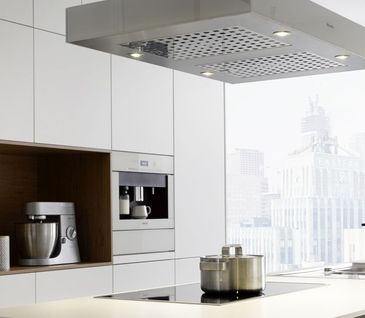 Moderne weiße Küche mit Inselhaube, Kochfeld, Backofern und eingebautem Kaffeevollautomat