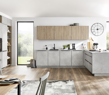 L-Küche in grauer Steinoptik mit E-Geräten und Hängeschränken in Holz mit passendem Essbereich.