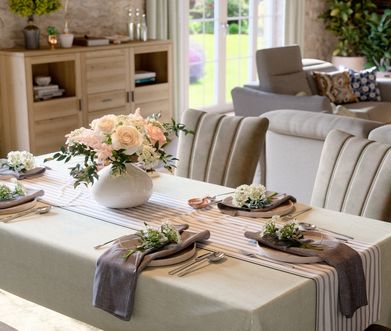 Gedeckter Esstisch mit vielen Blumen und Highboard mit Pflanzen