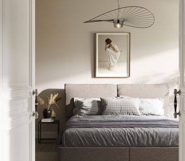 Anthrazitfarbenes Boxspringbett mit Gemälde an Wand und stilvoller Deckenleuchte