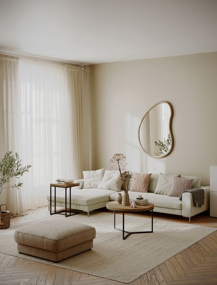 Helles Wohnzimmer im Hygge Stil: Beiges Ecksofa, hellbrauner Hocker, großer Teppich und dekorierte Beistelltische.