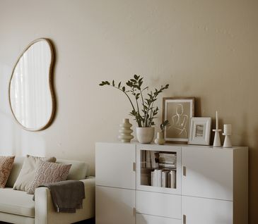 Gemütliches Wohnzimmer mit beigem Sofa und weißem Sideboard dekoriert mit Kerzen und Bildern.