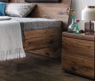 Dunkle Massivholzmöbel im Schlafzimmer aus Nussbaum: Bettgestell und Nachttisch