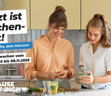 Mutter und Teenager-Tochter stehen gemeinsam in moderner Küche und kochen.