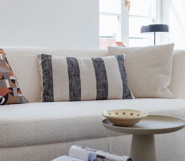 Beiges Sofa dekoriert mit verschiedenen Kissen.