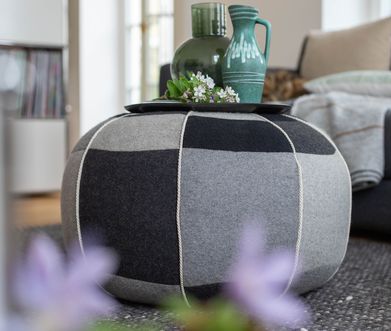 Hocker aus Stoff in verschiedenen Grautönen als Beistelltisch.