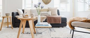 Helles Wohnzimmer im Hygge-Stil eingerichtet mit vielen Kissen, Decken und Fellen.