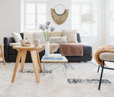 Helles Wohnzimmer im Hygge-Stil eingerichtet mit vielen Kissen, Decken und Fellen.