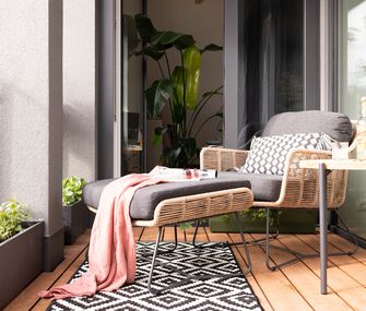 Gartensessel mit passendem Fußteil auf gemütlichem Balkon.