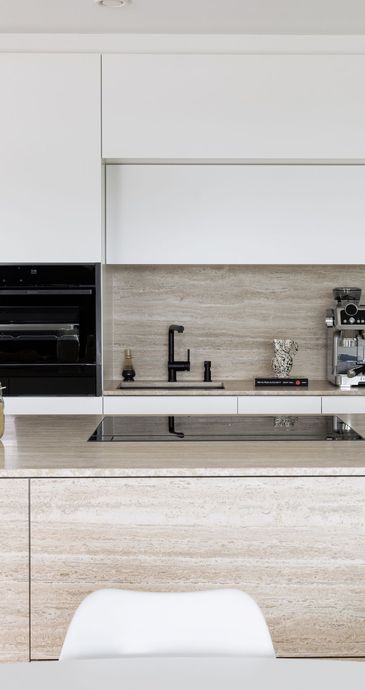 Moderne Inselküche mit deckenhohen Schränken und einem Siebträger auf der Arbeitsplatte.