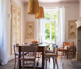 Esszimmer mit Tisch und Stühlen, großen Fenstern und Kamin.