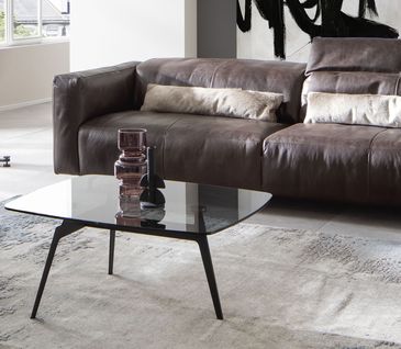 Elegantes Wohnzimmer mit hochwertigem Ledersofa und Couchtisch aus Glas.