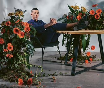 Mann sitzt auf Gartenstuhl und legt seine Beine auf einem runden Gartentisch ab.