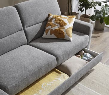 Praktischer, ausziehbarer Bettkasten eines grauen Sofas.