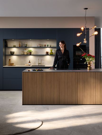 Elegante Inselküche mit Kücheninsel mit Holzfront und dunkelblauer Küchenzeile inkl. indirekter Beleuchtung.