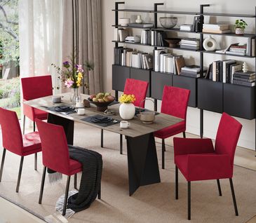 Ein Festmahl für die Sinne: Die Farbe Rot im Esszimmer. Esszimmer mit roten Stühlen um Esstisch mit modernem, schwarzem Regal.