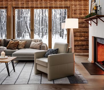 Weihnachtlich dekoriertes Wohnzimmer im Chalet-Style mit Kamin, großem Ecksofa und passendem Sessel.