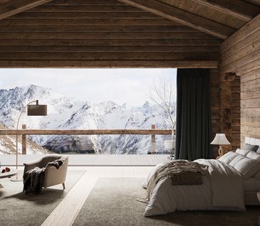 Schlafzimmer im Chalet-Stil in Holzblock-Hütte mit Bett, Sessel, Beistelltisch und Lampe in gedeckten Farben und urigem Stil mit Blick auf Berglandschaft.