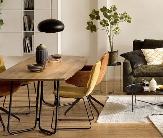 Bunte Stühle am Esstisch Erik im Wohnbereich neben grünem Cordsofa