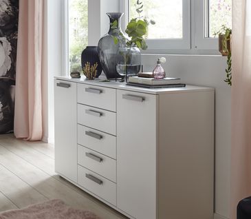 Weiße Kommode mit silbernen Griffen dekoriert mit vielen Vasen