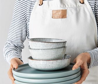 Person trägt Keramikgeschirr, passend zum Landhausküchenstil