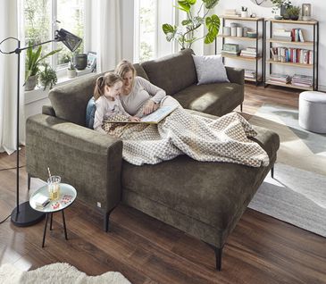 Grünes Ecksofa in hellem Wohnzimmer.