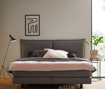 Graues Boxspringbett mit rosa Bettwäsche