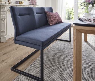 Tiefblaue Sitzbank mit Kufengestell vor einem Holzesstisch mit Dekokissen