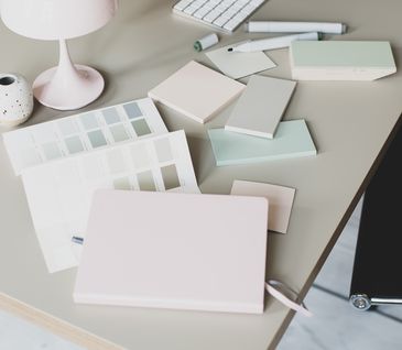 Aufgeräumter, stilvoller Schreibtisch mit vielen bunten Blöcken und einem PC