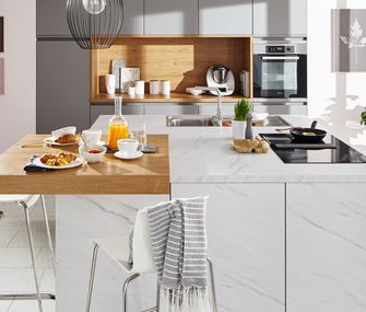 Mit Frühstückstresen wird die Kücheninsel schnell zum geliebten Mittelpunkt! Kücheninsel in Marmoroptik mit Holzakzenten und Barhockern