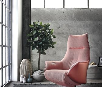 Rosa Sessel aus Stoff und Leder vor grauer Betonwand in minimalistischem Ambiente