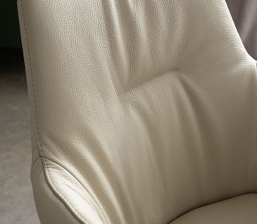 Detailaufnahme eines edlen Lederstuhls in Beige mit Armlehnen.