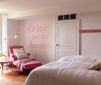 Rosa eingerichtetes Schlafzimmer mit Doppelbett, pinkem Relax-Sessel und rosa Beistelltisch.