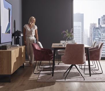 Verschiedenfarbige Stühle um einen Esstisch in Esszimmer.