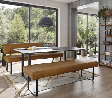 Modernes Esszimmer mit Esstisch und zwei Bänken in braunem Leder.