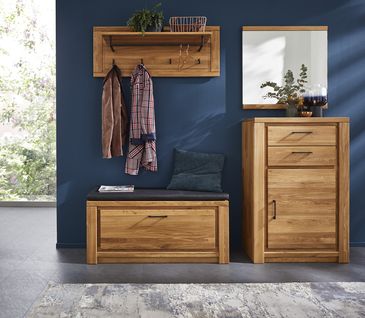 Garderoben-Set aus Massivholz vor dunkelblauer Wand dekoriert mit Jacken, Pflanzen und einem blauen Kissen.